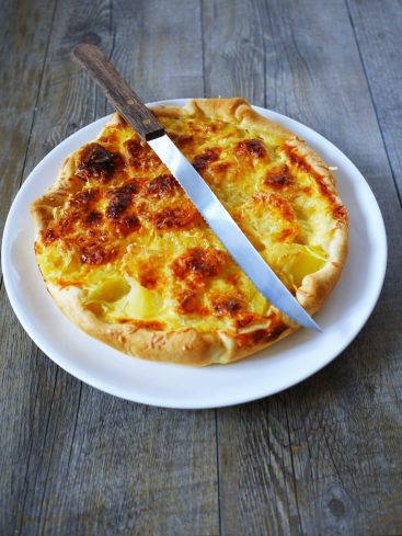 Tarte aux pommes de terre coupée avec un couteau.