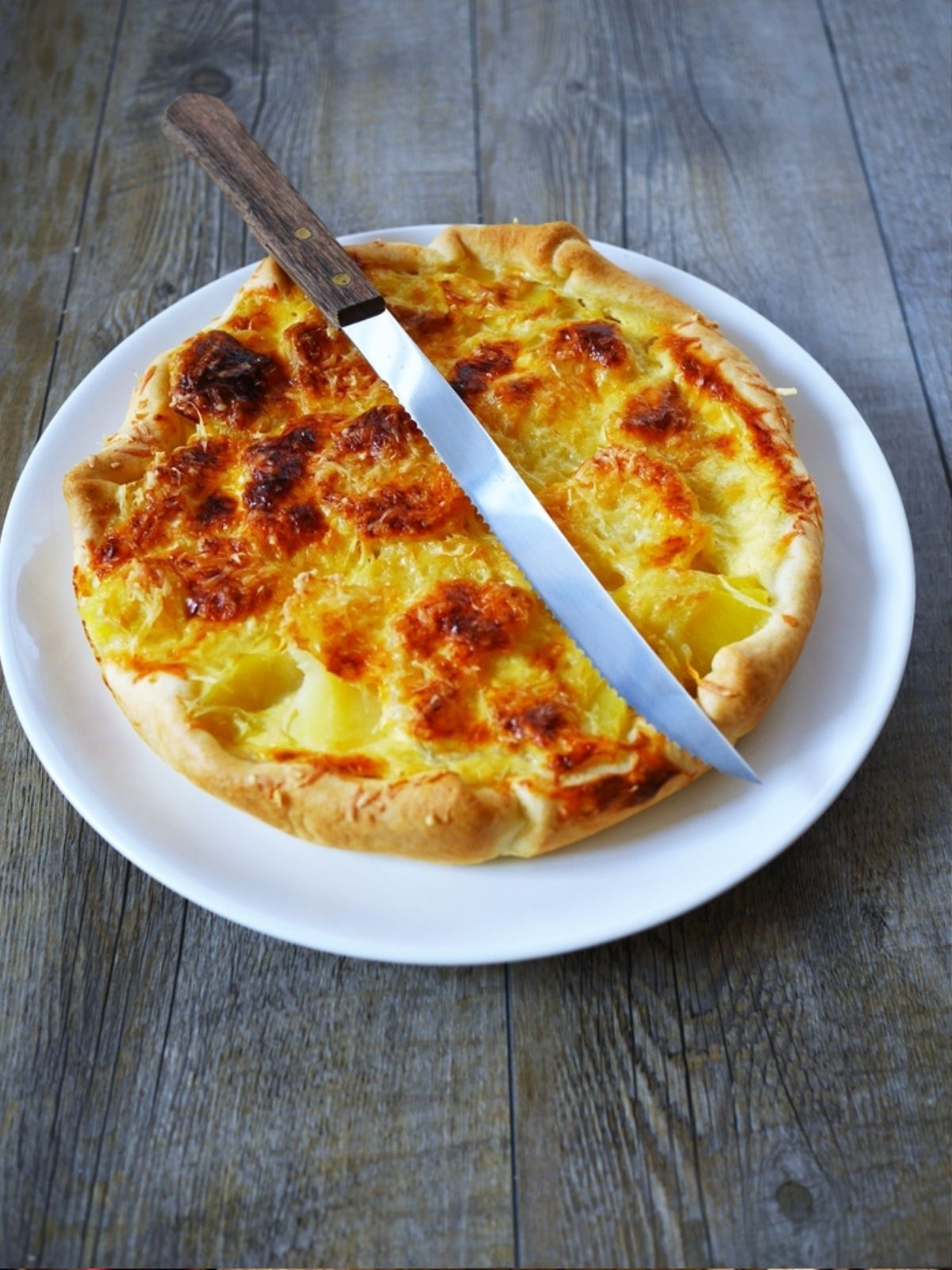 Quiche lorraine avec couteau sur assiette blanche