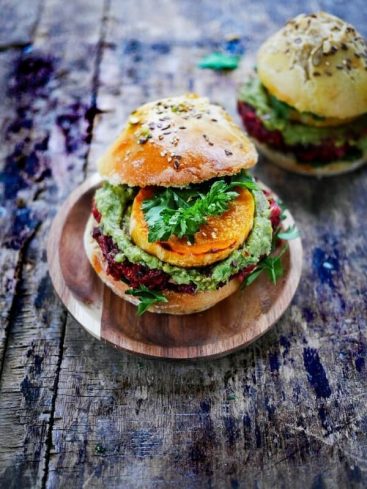 Burger végétarien coloré sur une planche en bois rustique.