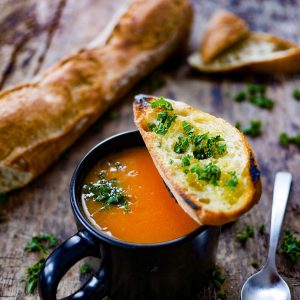 Soupe, pain grillé à l'ail et persil sur bois.