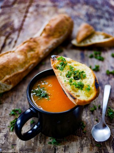 Soupe, pain grillé à l'ail et persil sur bois.
