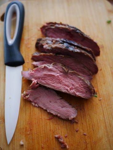 Filet de boeuf tranché, saignant, sur planche à découper