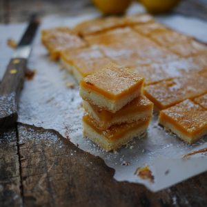 Carrés au citron saupoudrés de sucre glace sur bois.