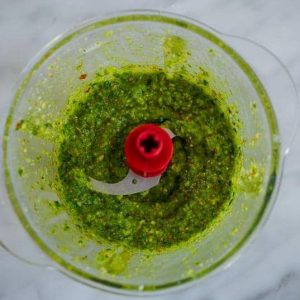 Pesto vert fraîchement préparé dans un robot culinaire.