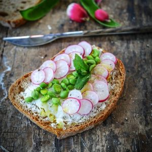 Tartine radis, fèves et menthe sur table rustique