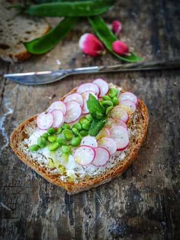 Tartine radis, fèves et menthe sur table rustique