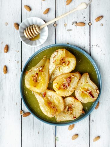 Poires pochées au miel et amandes sur assiette.