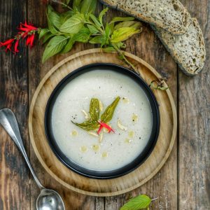 Assiette de soupe, pain et fleurs sur table en bois.