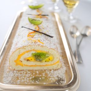 Gâteau roulé coco, kiwi, mangue sur plateau argenté.