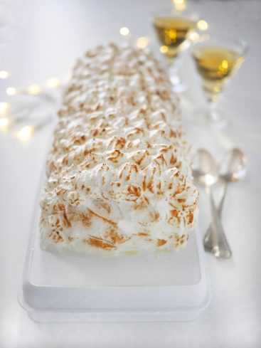Bûche meringuée festive avec champagne et lumières.