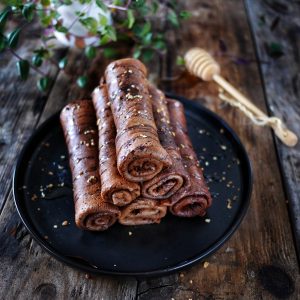 Crêpes au chocolat roulées avec miel et plante verte.