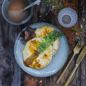 Plat de poisson avec sauce, champignons et jeunes pousses.
