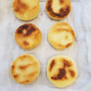 Six arepas dorées sur papier sulfurisé.