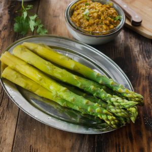 Asperges vertes, sauce, et coriandre sur table en bois