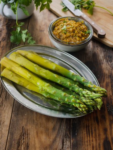Asperges vertes, sauce, et coriandre sur table en bois