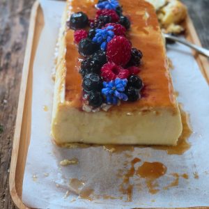 Flan au caramel décoré de fruits rouges et fleurs.