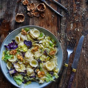 Salade d'orecchiette au chou et noix sur bois rustique.