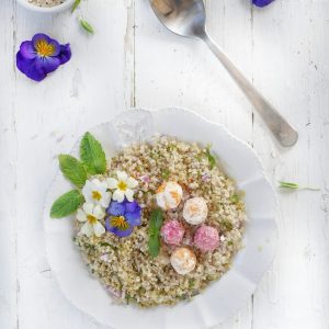 Salade de quinoa avec fleurs comestibles et boules de fromage.