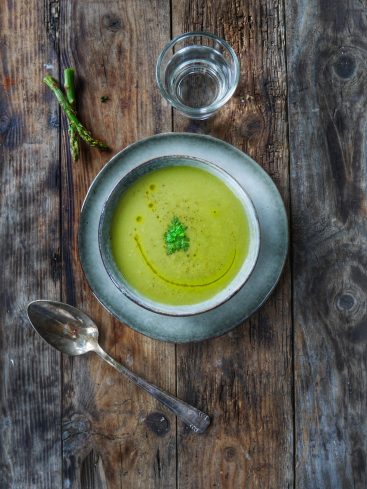Soupe d'asperges crémeuse sur table en bois rustique.