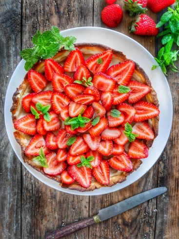 Tarte aux fraises et menthe sur table en bois.
