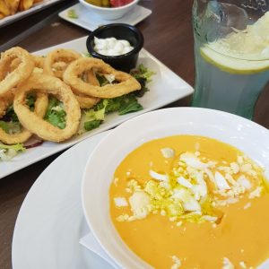 Repas avec gaspacho, calamars frits, olives et citronnade.
