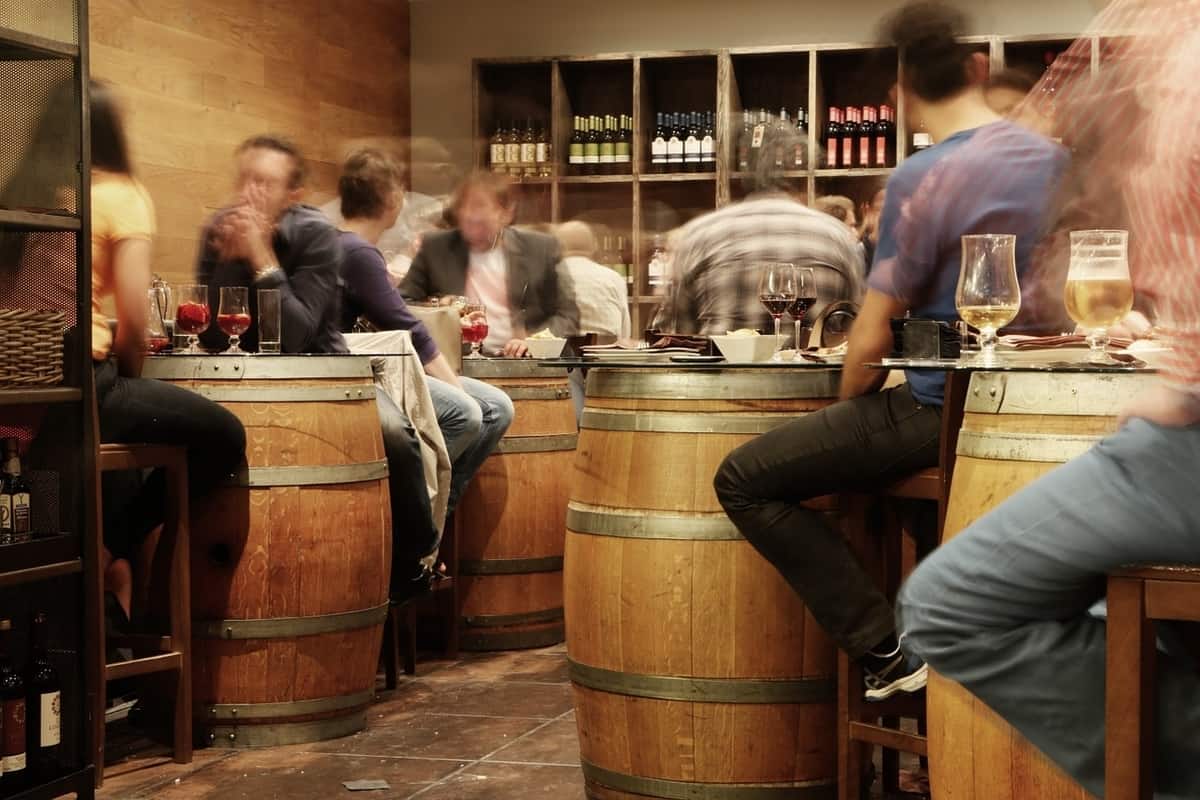 Restaurant animé avec tables faites de tonneaux de vin.
