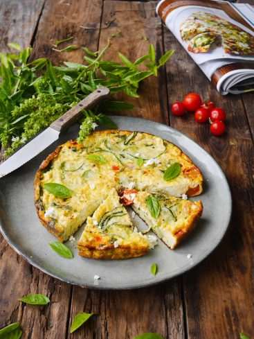 Quiche aux courgettes, tomates et basilic sur table en bois