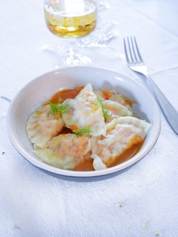 Assiette de ravioles sauce crémeuse, verre de boisson.