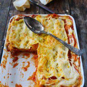 Lasagnes gratinées avec pain et cuillère sur table rustique.
