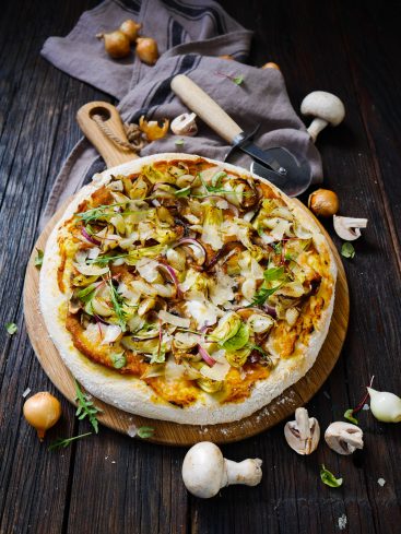 Pizza artisanale aux légumes sur planche en bois.