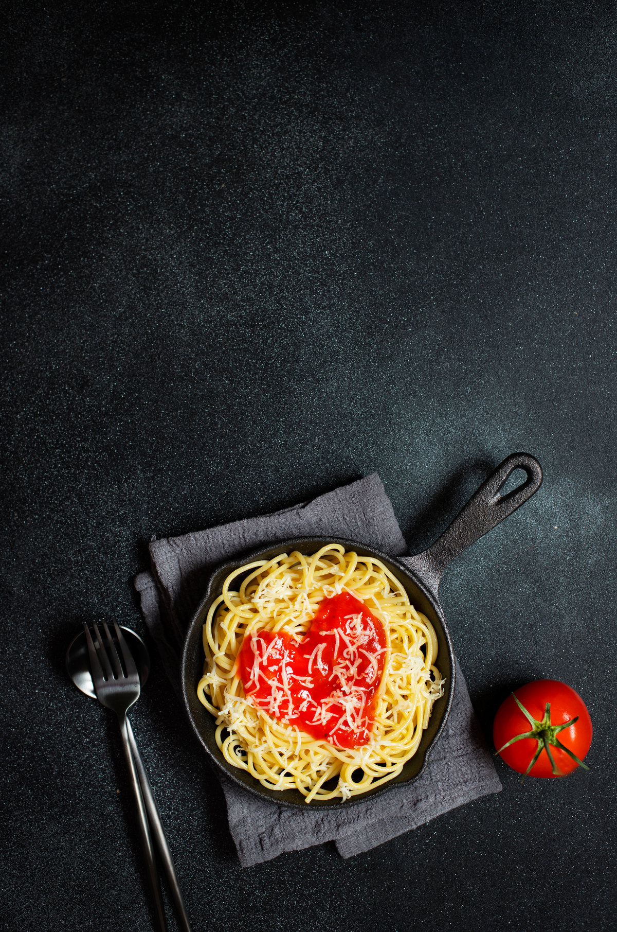 Spaghetti cœur tomate, parmesan, poêle en fonte, fond noir