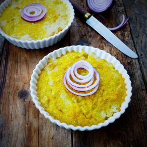Gratins individuels avec oignon rouge sur table en bois.