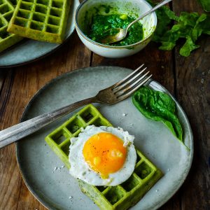 Gaufre verte, œuf au plat et épinards sur bois.