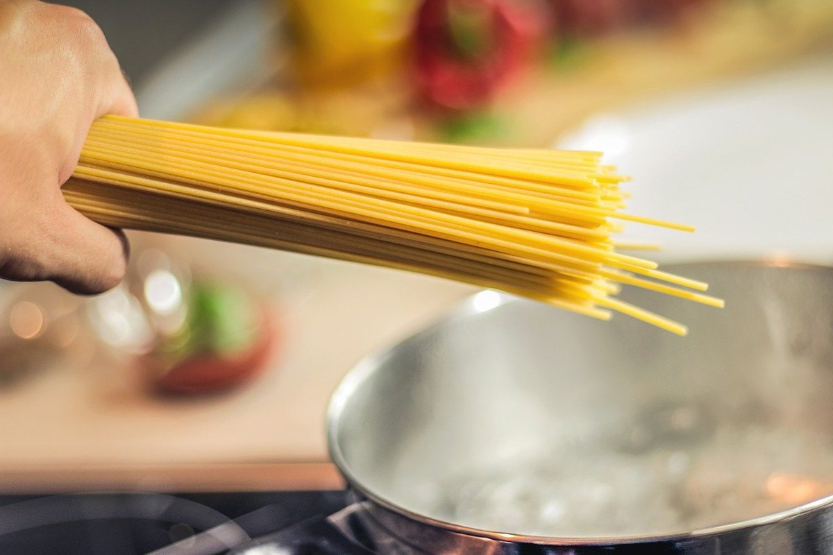 Spaghettis crus au-dessus d'une casserole d'eau bouillante.
