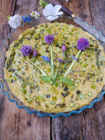 Quiche aux asperges et fleurs comestibles sur table bois