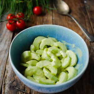 Salade de concombres crémeuse dans un bol bleu.