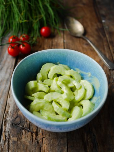 Salade de concombres crémeuse dans un bol bleu.