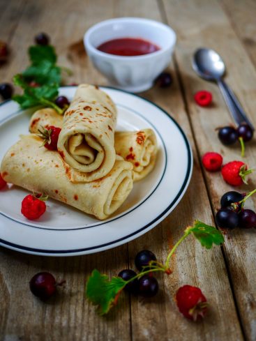 Crêpes roulées avec fruits rouges et sauce sur bois