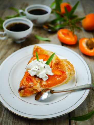 Tarte abricot, crème fouettée et café sur table rustique.