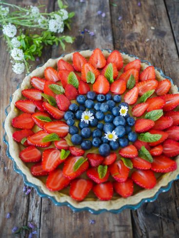 Tarte aux fraises et myrtilles sur fond bois.