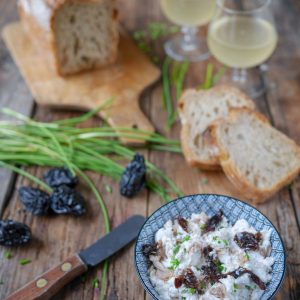 Pain, fromage de chèvre, pruneaux, vin blanc sur bois