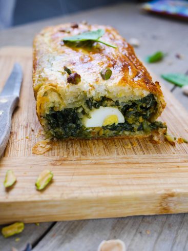 Pâté en croûte épinards, œuf, pistaches sur planche bois