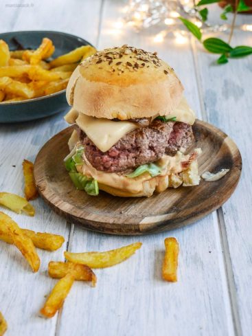 Hamburger avec frites sur plateau en bois.