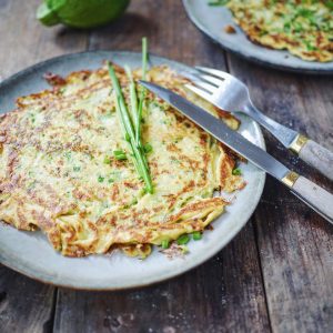Galette de courgette, ciboulette, fourchette et couteau sur bois