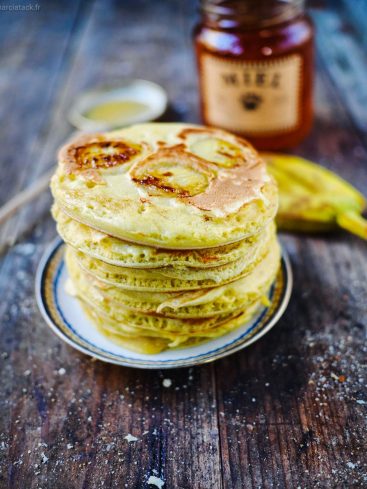 Pancakes à la banane et miel sur table bois.