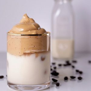 Café Dalgona crémeux dans un verre avec lait et grains.
