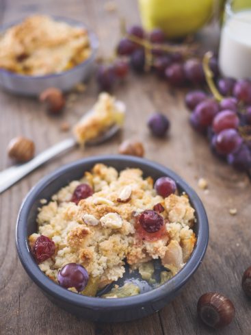 Crumble aux fruits, raisins, noisettes sur table en bois.