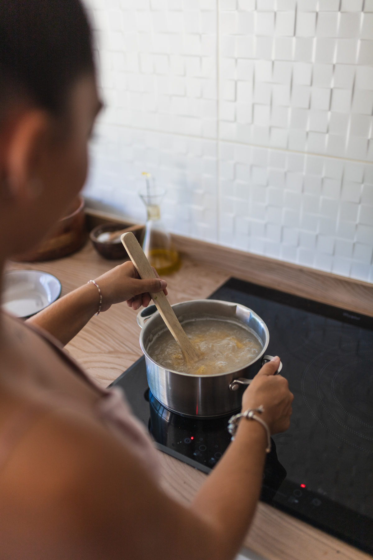 Femme préparant des pâtes dans une cuisine moderne.