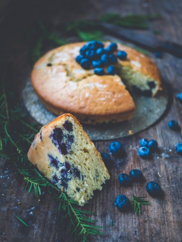 Gâteau aux myrtilles, part coupée, sur table en bois.