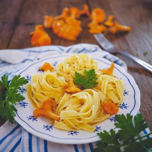 Pâtes fraîches aux girolles et persil sur table bois